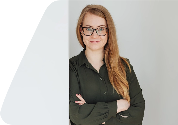 Junge, grinsende Person mit Seitenscheitel, langem, goldblondem Haar, Brille und khakifarbener Bluse.